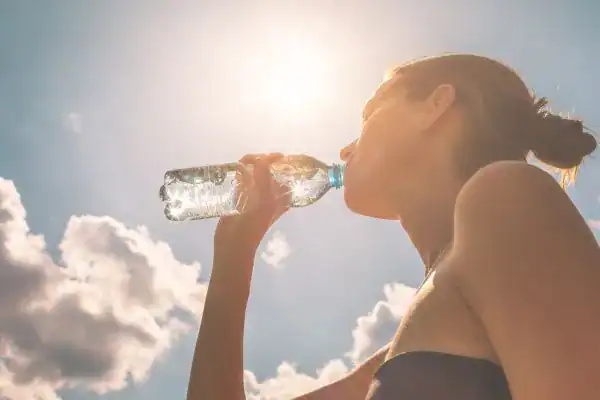 Hydration: The Secret Ingredient for a Toned Stomach and Enhanced Fitness 3 Image of woman drinking water to hydrate Isle of Isla after run.