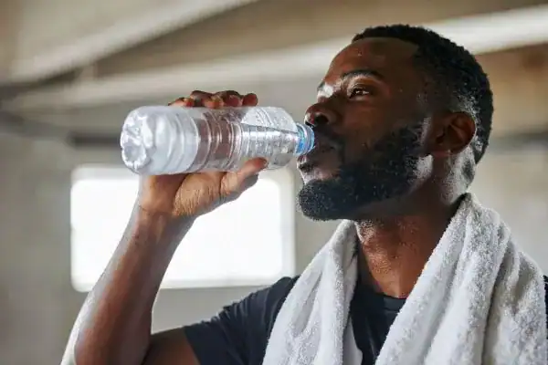 Hydration: The Secret Ingredient for a Toned Stomach and Enhanced Fitness 1 Image of man drinking water to improve hydration Isle of Isla after work out.